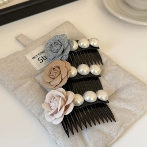 Détail de trois peignes à cheveux avec roses en tissu et perles sur lin doux