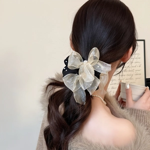 Polka dot mesh bow scrunchie with pearls worn on low ponytail for elegant style