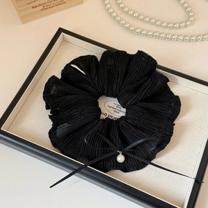 Détail du chouchou noir plissé avec un nœud en ruban et une élégante perle