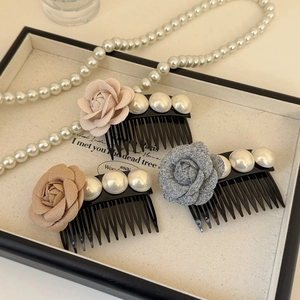 Détail de trois peignes à cheveux rose en tissu avec perles sur un plateau en lin