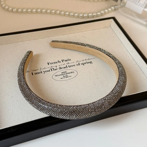 Close-up of luxury rhinestones headband with grey crystals on a beige jewelry tray