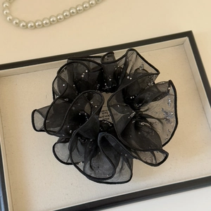 Détail d'un chouchou en tulle noir orné de paillettes argentées et couches d'organza