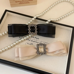 Detail showing elegant ribbon bow hair clip with sparkling rhinestone square buckle decoration