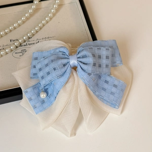 Detail of light blue checkered bow hair clip with small pearl pendant on chiffon fabric