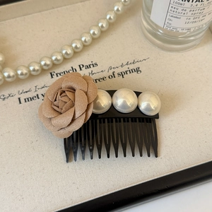 Détail d'un peigne à cheveux avec fleur de camélia et perles sur tissu texturé