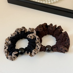 Detail of leopard print scrunchies with elastic pleats and decorative black round beads