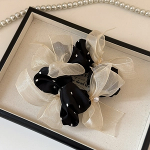 Detail of a mesh polka dot bow scrunchie featuring elegant pearls and satin texture