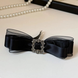 Macro detail of black satin bow hair clip with luxury rhinestone square buckle