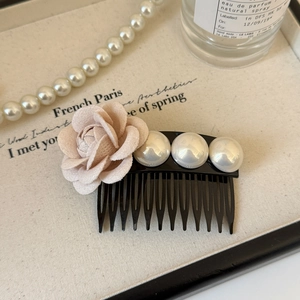 Détail d'un peigne élégant orné d'une rose en tissu rose et de trois perles blanches polies