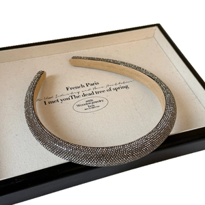 Elegant padded headband with sparkling grey rhinestones on a vintage display tray