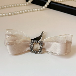 Detail of champagne bow hair clip with rhinestone square buckle and satin organza layers
