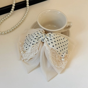 Détail d'un nœud papillon en dentelle à pois avec perles posé sur une tasse en céramique