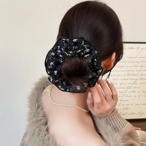 Chouchou en mousseline à imprimé fleuri avec collier de perles dans une scène chaleureuse
