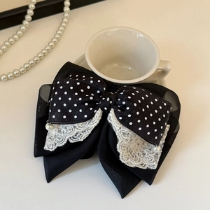 Gros plan d'un nœud papillon à pois noirs avec dentelle et pendentifs perles élégants