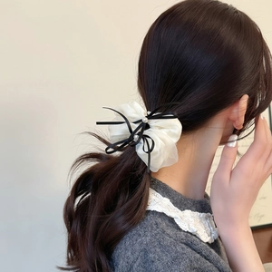 Chouchou élégant en organza blanc avec nœud noir et perles sur une queue de cheval