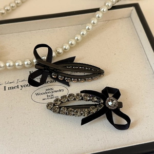 Barrettes à cheveux nœud noir et strass brillants présentées sur un plateau chic