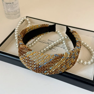 Close-up of wide tweed headband with brown and blue woven texture in a luxury setting