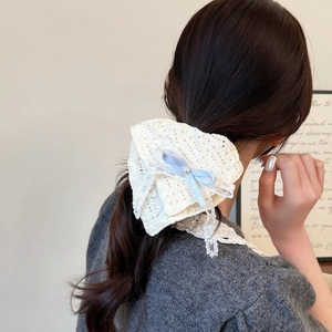 Dettaglio dello scrunchie in pizzo con fiocco di seta azzurro e perla sulla coda