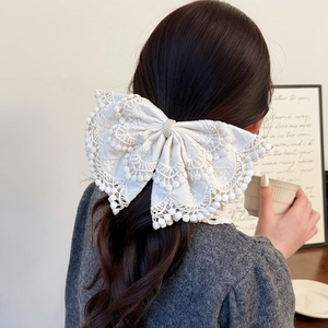 Close-up of white lace bow hair clip with pearl detailing on back of head