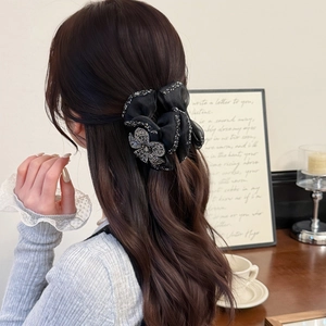 Black organza hair scrunchie with rhinestones and bow accent shown on hair