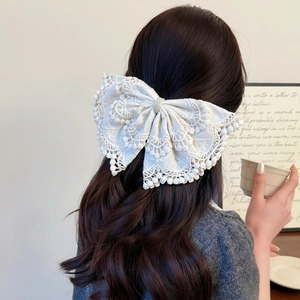 Elegant white lace bow hair clip with pearls shown on model's head from behind