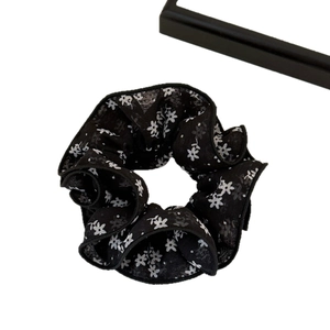 Chouchou en tissu noir avec imprimé fleurs blanches pour une coiffure élégante