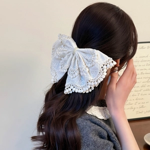 Bohemian oversized white lace bow hair clip with pearls shown on long brown hair