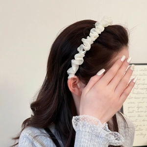 Elegante cerchietto in tulle bianco a pieghe con fibbia a cuore su lunghi capelli castani