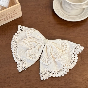 Detail of bohemian cream lace bow hair clip with elegant pearl beads on a wooden desk