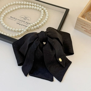 Elegant black satin bow hair clip with gold metal tag and refined French style design