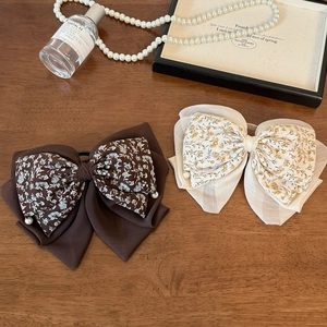 Elegant floral chiffon bow hair clips with pearls on a wooden decorative background