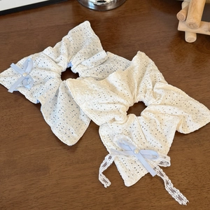 Dettaglio di elastici in pizzo con fiocchi di nastro azzurro e perle bianche lucide