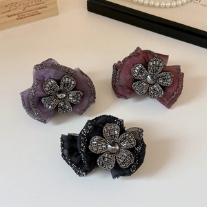 Detail view of sparkling rhinestone flower hair claws in purple, burgundy, and black mesh