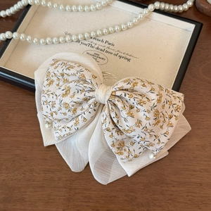 Detail of elegant French floral bow hair clip with pearls on a wooden aesthetic background