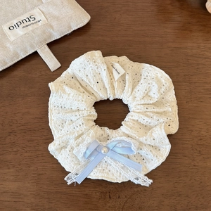 Dettaglio di elastico per capelli in pizzo bianco con fiocco azzurro e perla centrale