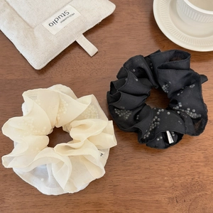 Close-up of elegant pearl-embellished mesh hair scrunchies on a wooden background
