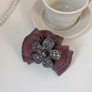 Detail view of burgundy mesh bow hair clip with rhinestone flower on white background