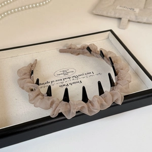 Dettaglio del cerchietto in tulle beige con denti antiscivolo e texture a rete pieghettata