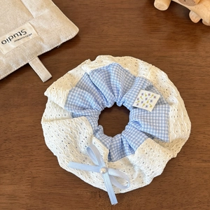 Dettaglio dell'elastico a quadretti blu con bordo in pizzo bianco e fiocco di perle