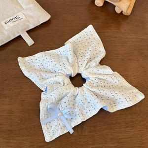 Dettaglio di un elastico in pizzo bianco a pois blu con fiocco di perle e nastro