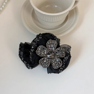 Close-up of black mesh flower hair claw clip with silver rhinestones and grey gemstone