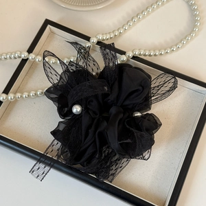 Détail d'un chouchou en organza noir avec dentelle et perles élégantes au centre