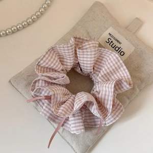 Dettaglio di elastico a scacchi rosa con nastri su borsa di lino per un dolce stile