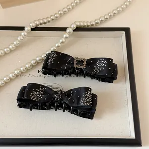 Detail of elegant black satin bow banana clips with sparkling rhinestone embellishments