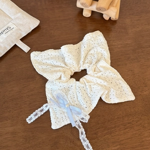 Dettaglio dell'elastico in pizzo bianco con fiocco di seta azzurro, perla e nastri