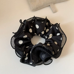 Detaillierte Nahaufnahme eines schwarzen Polka-Dot-Haargummis aus Mesh mit Rüschenverzierung