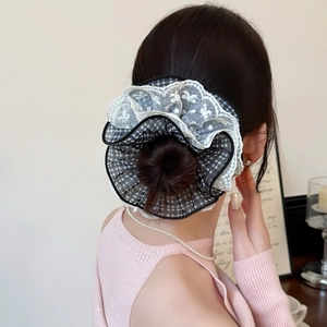 Detail of black plaid scrunchie with white lace embroidery on a model bun hairstyle