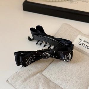 Close-up of elegant black ribbon bow banana clip with shimmering silver rhinestone details