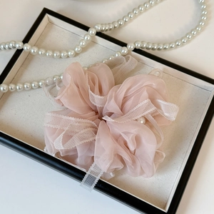 Détail du chouchou en organza rose avec bordure en dentelle blanche et perles
