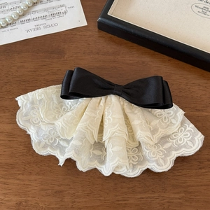 Detailed close-up of French vintage black satin bow and white floral lace hair clip